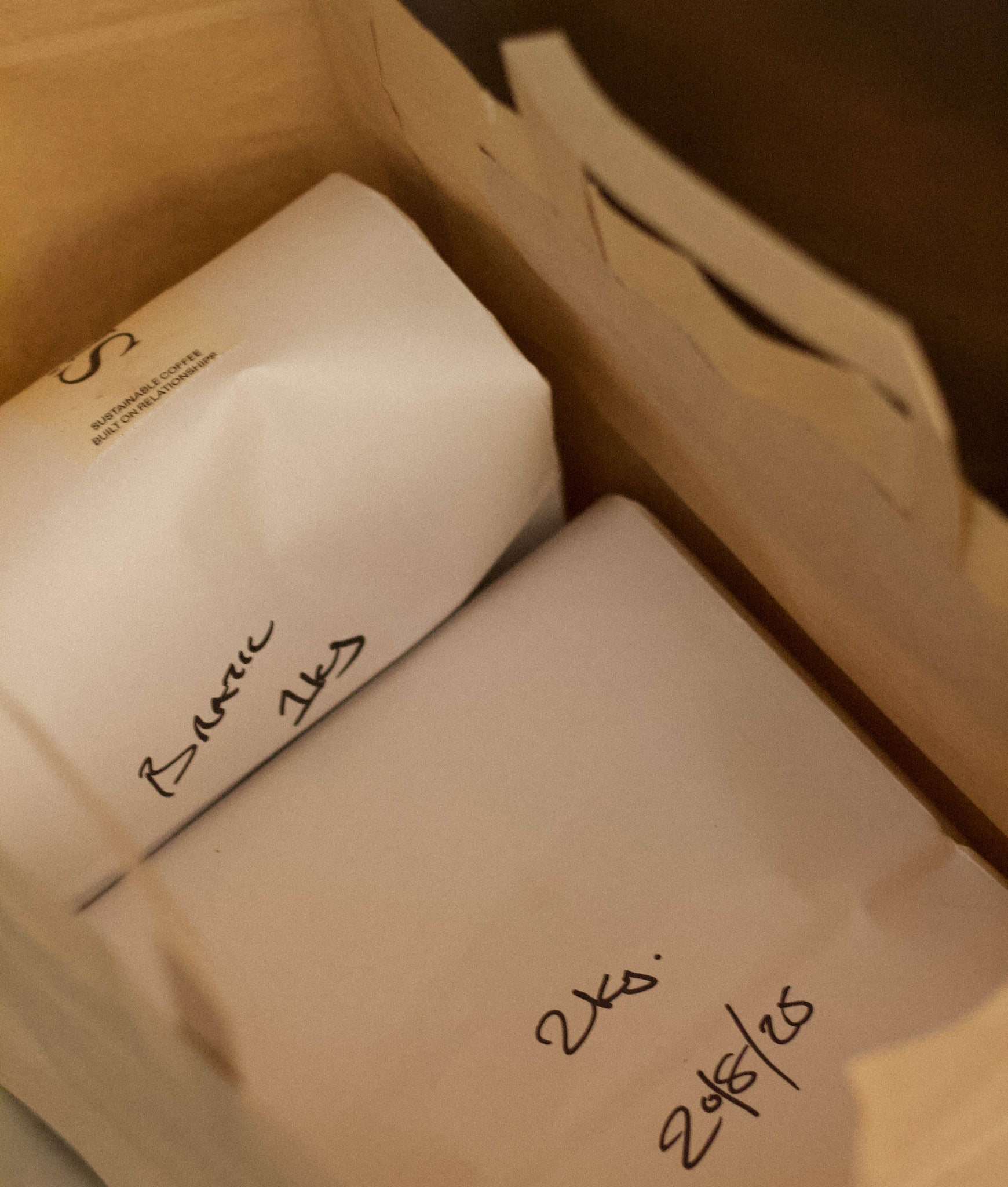 Two white boxes with handwritten labels inside a cardboard box.